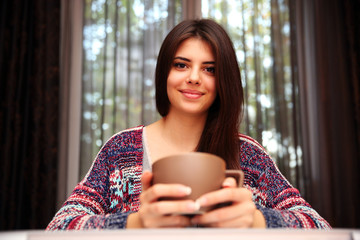 Wall Mural - Happy beautiful woman sitting at the table with cup of coffee