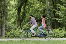 Young Couple Riding On The Tandem Bicycle