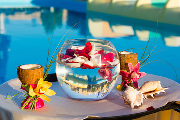 two glasses of coconut with orchids, two seashells in a fishbowl