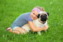Little Girl And Her Pug Dog On Green Grass