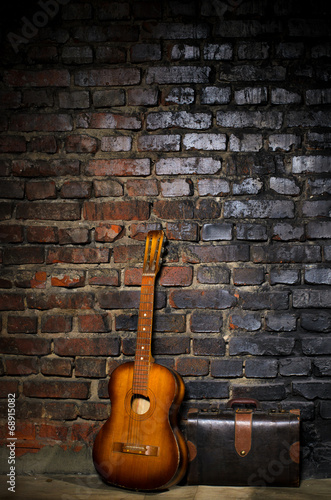 Obraz na płótnie canvas czteroczęściowy "tetraptyk" Gitara i retro torba na tle ceglanego muru