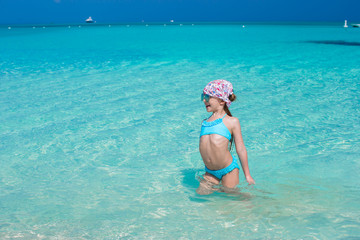 Wall Mural - Adorable little girl in the sea on tropical beach vacation