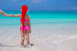 © travnikovstudio - Little cute girl in red Santa hat on tropical beach