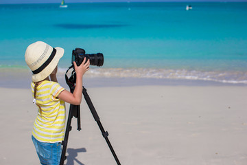 Wall Mural - Little girl shooting with camera on tripod during her summer