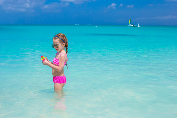 Sticker - Cute little girl playing with toys during caribbean vacation