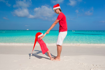 Wall Mural - Little girl and happy dad in Santa Hat have fun at tropical