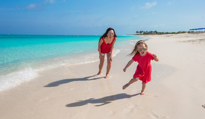 Wall Mural - Young mother and little girl have fun at tropical beach