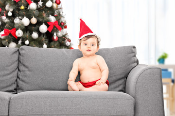 Canvas Print - Baby with santa hat and Christmas tree behind her