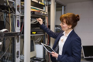 Poster - Pretty technician using tablet pc while fixing server