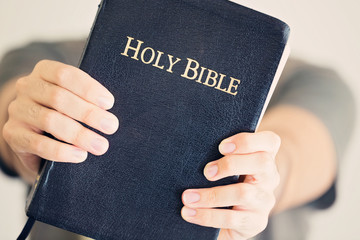 Close up of a young man holding out his Bible