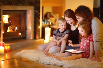 happy family using a tablet pc by a fireplace