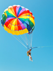 Poster - girl parascending on parachute in blue sky