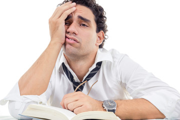 tired man with glasses in white shirt sitting with book