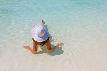 Wall Mural - Woman sitting in a swimming pool in a sunhat