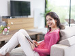 © jackfrog - cheerful woman on a couch at home using digital tablet