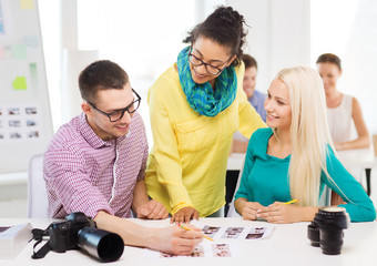 Poster - smiling team with printed photos working in office