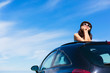 Relaxed woman on summer vacation leaning out sunroof