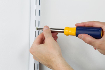 Installing metal bracket on Wall with hand screwdriver