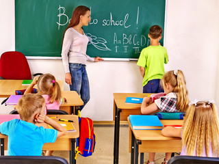 Children in classroom near blackboard.