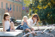 © MNStudio - Young woman and two kids by a city fountain