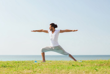 Canvas Print - smiling man making yoga exercises outdoors