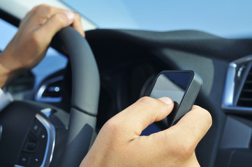 man using a smartphone while driving a car