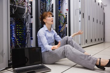 Wall Mural - Stressed technician sitting on floor beside open server