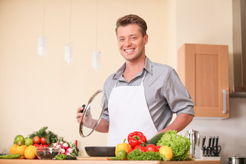 waist up of man holding frying pan lid.