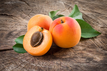 Organic apricots with leaves on wooden background