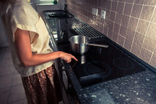 Young Woman In Kitchen Cooking With Saucepan