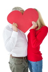 Wall Mural - Couple embracing and holding heart over faces