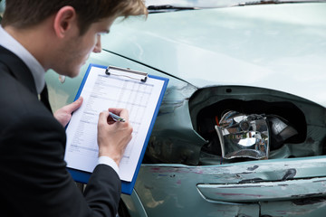 Insurance Agent Examining Car After Accident