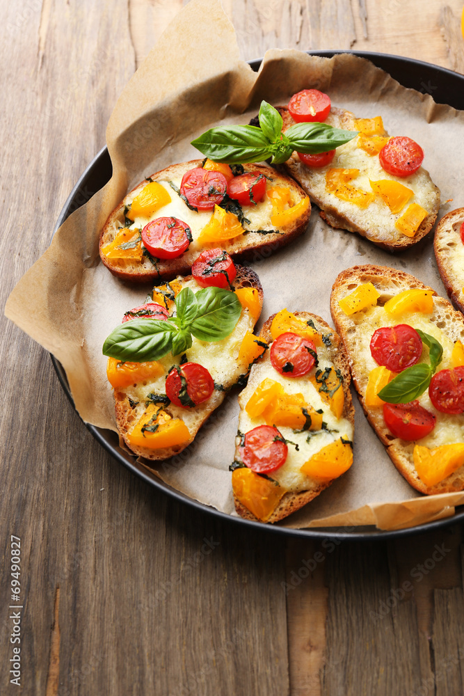 Tasty bruschetta with tomatoes on pan, on old wooden table