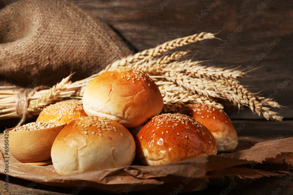 Tasty buns with sesame on wooden background