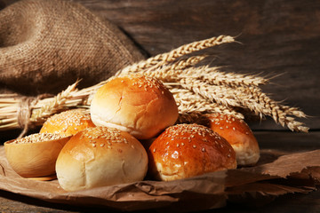 Sticker - Tasty buns with sesame on wooden background