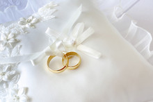 Gold Wedding Rings On A Pillow With Ribbons