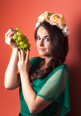 beautiful young woman wearing wreath and holding green grapes ag