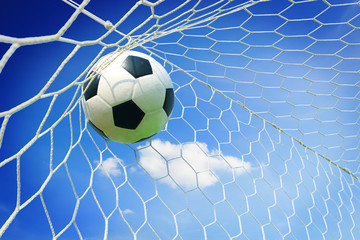 soccer ball in goal with blue sky