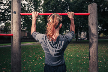 Young woman doing pullups in the park