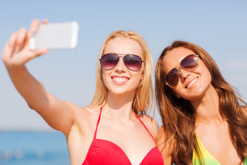 Sticker - two smiling women making selfie on beach