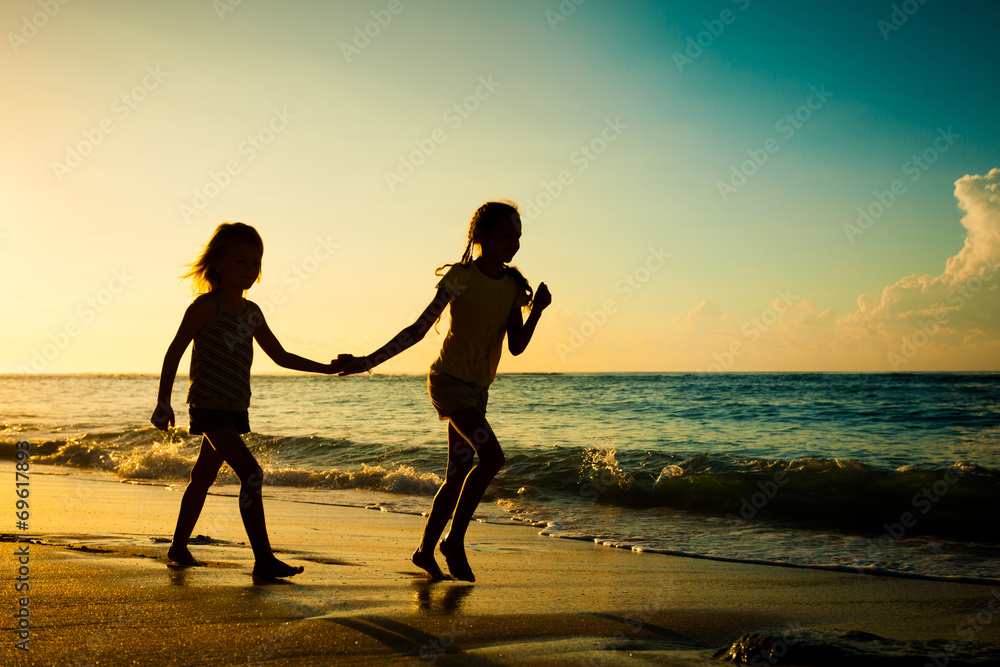 happy kids playing on beach at the sunrise time - obrazy, fototapety, plakaty 