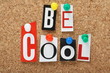 The phrase Be Cool in cut out letters on a cork notice board