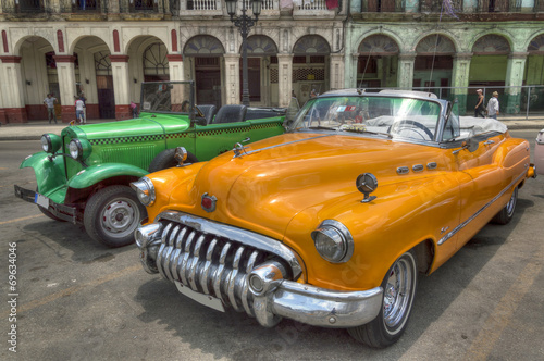 Fototapeta na wymiar Orange and green cars in front of Capitolio, Havana, Cuba