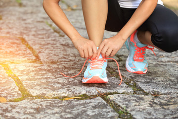 Wall Mural - woman runner tying shoelace on stone trail