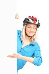 Wall Mural - Female biker with helmet standing behind a panel