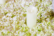 The big white candle in a wreath from artificial flowers. A wedd