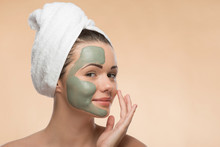 Spa Girl With A  Towel On Her Head Applying Facial Clay Mask And