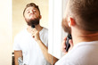 © Africa Studio - Young man shaving his beard in bathroom