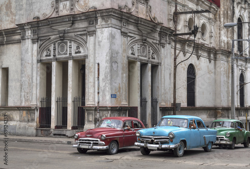 Naklejka na szybę Cuban taxis passing under an old church in Havana