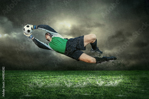  Fototapeta piłkarska   gracz-futbolu-z-pilka-w-akci-pod-deszczem-outdoors
